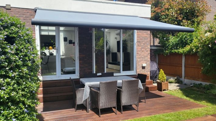 Intelroll INT500 retractable garden patio awnings in London installed colour grey cassette and grey fabric full cassette in front view above garden furniture set