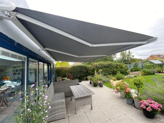 Intelroll INT500 retractable awnings in UK installed side view white cassette grey fabric
